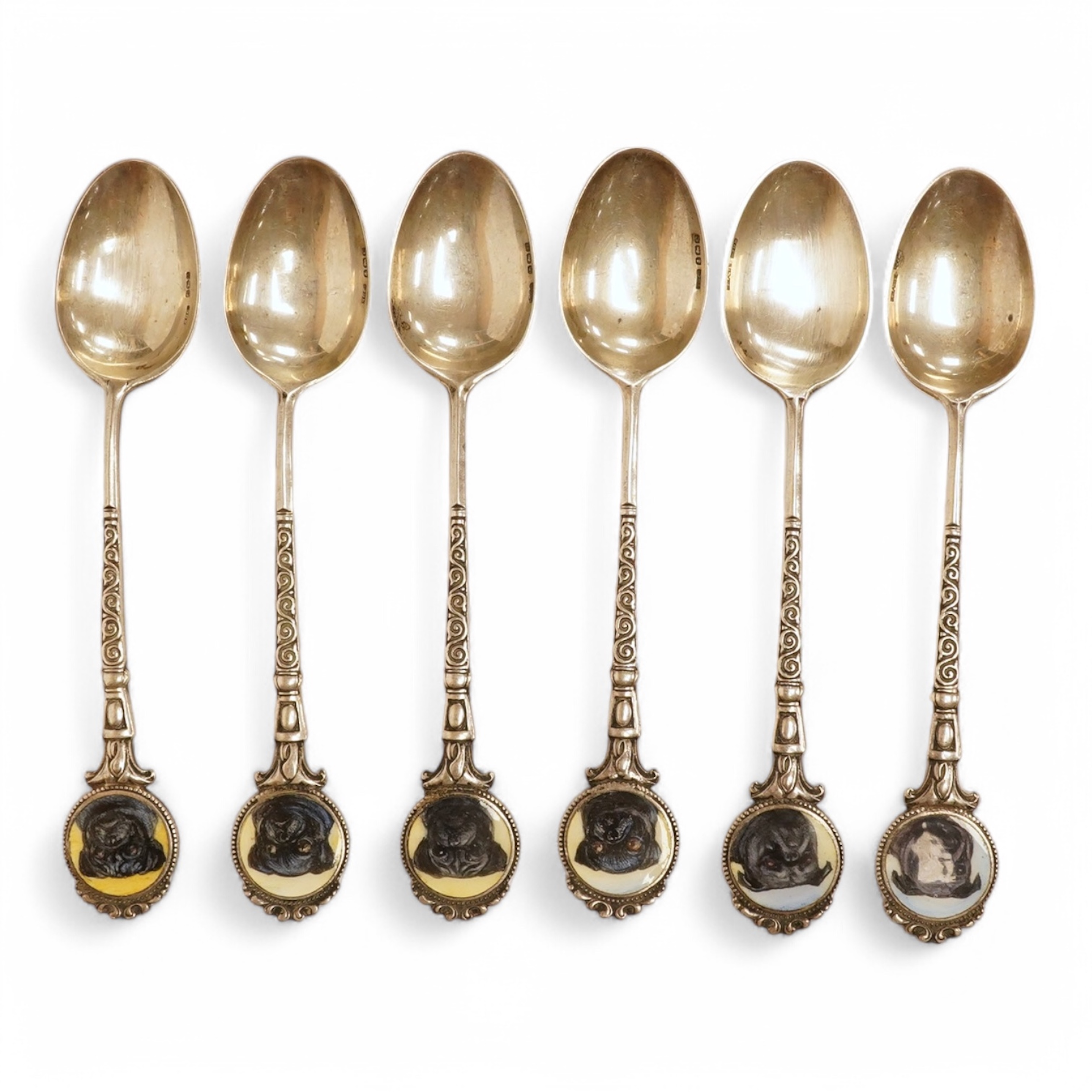 A matched set of six mainly George V silver/white metal and enamel teaspoons, with terminals decorated with dog's heads, 13.6cm. Condition - fair